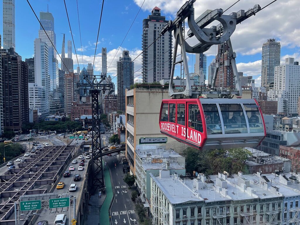 Red Roosevelt Island Tramway cabin above Manhattan streets