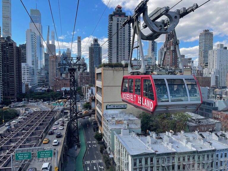 Red Roosevelt Island Tramway cabin above Manhattan streets