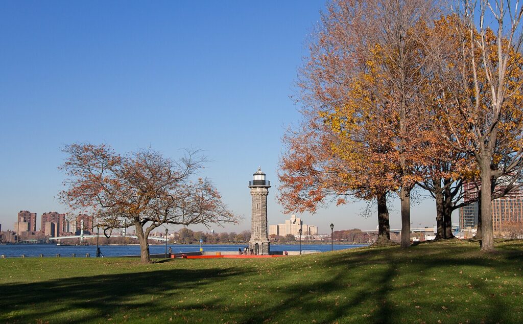 Roosevelt Island lighthouse beside a lawn and autumn trees